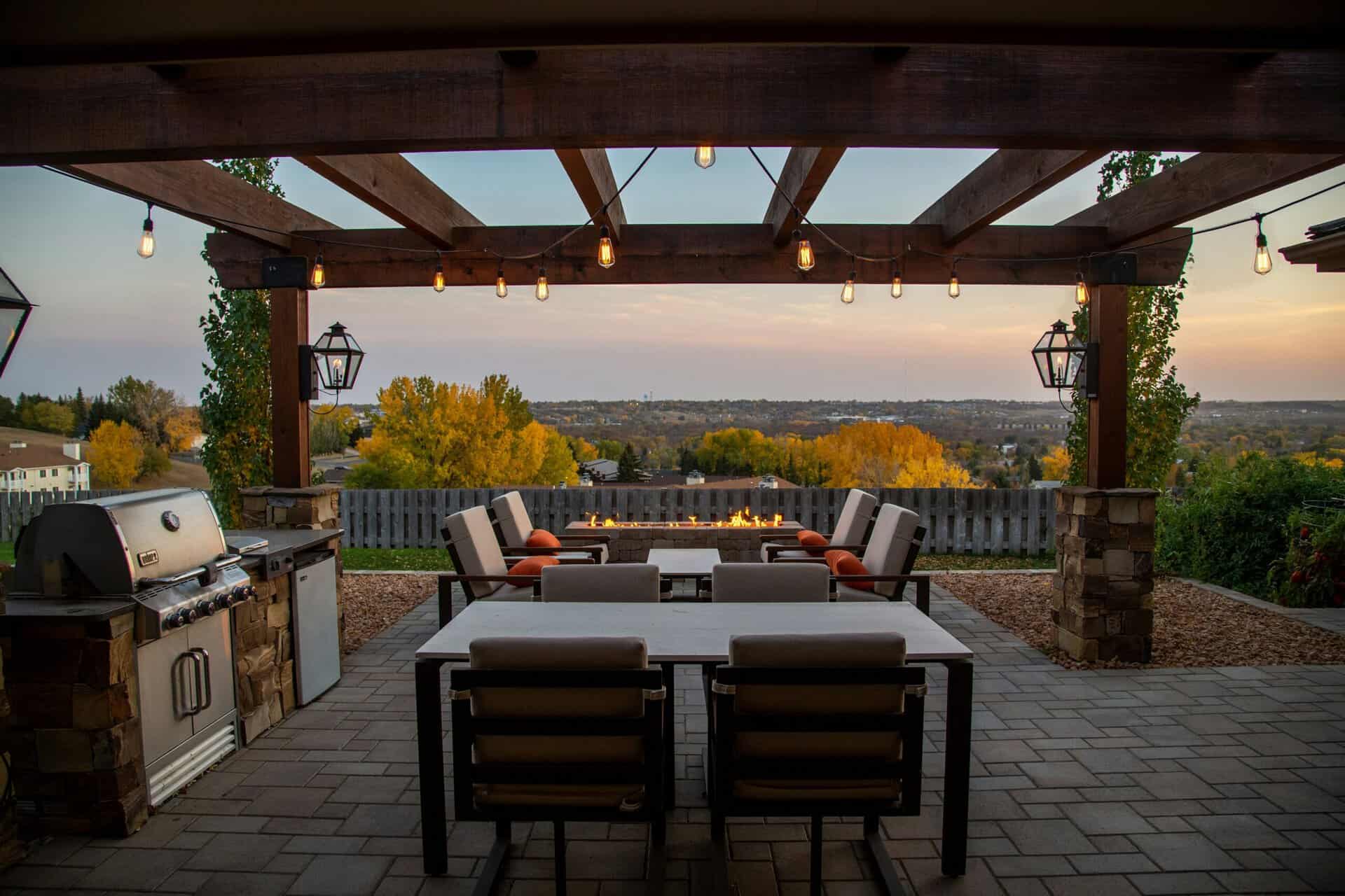 Outdoor patio with stone pavers, pergola, and modern outdoor kitchen and seating area.