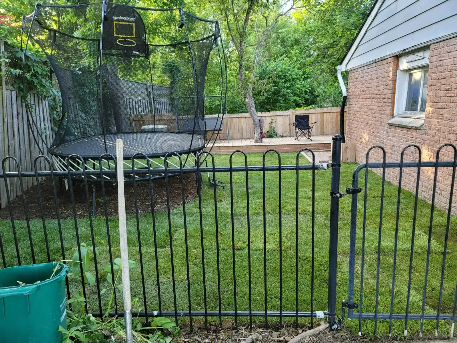 Black ornamental steel fencing and trampoline in a residential backyard.